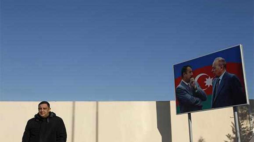 Oil worker Namik Aliyev stands next to a billboard of Azerbaijan's President Ilham Aliyev (L) and his father late President Haidar Aliyev, as he waits for a helicopter on the island of Chilov in the Caspian Sea, about 70 km (44 miles) east of Baku, January 23, 2013. Aliyev, 32, like the country of Azerbaijan itself, has oil in his blood. His father and grandfather both worked in oil production, an industry which dates back to the 19th century in Azerbaijan and contributes more than half of the country's gro