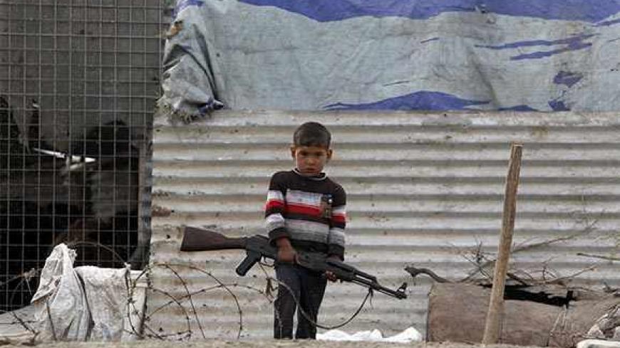 A boy carries a AK47 rifle at the Chebayesh marsh in Nassiriya, 300 km (185 miles) southeast of Baghdad, February 15, 2013. The Marsh Arabs who had farmed this area for thousands of years, were badly affected by a campaign mounted by the government of Saddam Hussein in the 1990s to destroy their lifestyle. The marshes were drained of water, and hundreds of thousands of Marsh Arabs were forced to flee to cities, where they live in poverty, the locals in this area said. Picture taken February 15.    REUTERS/T