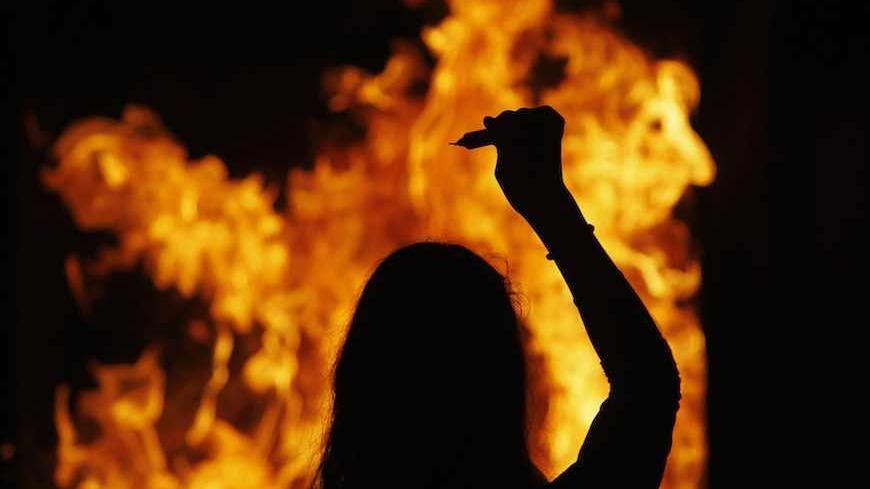 A Jewish worshipper throws a candle into a fire during a ceremony marking the 19th anniversary of the death of Rabbi Shalom Ifergan at his grave-site in the southern town of Netivot June 13, 2013. Organised by Rabbi Shalom Iregan's son, Rabbi Yaakov Yisrael Ifergan, the annual memorial ceremony draws hundreds of Israelis who throw candles into a bonfire near the Rabbi's grave-site. Picture taken June 13, 2013. REUTERS/Amir Cohen (ISRAEL - Tags: RELIGION ANNIVERSARY TPX IMAGES OF THE DAY) - RTX10NEP