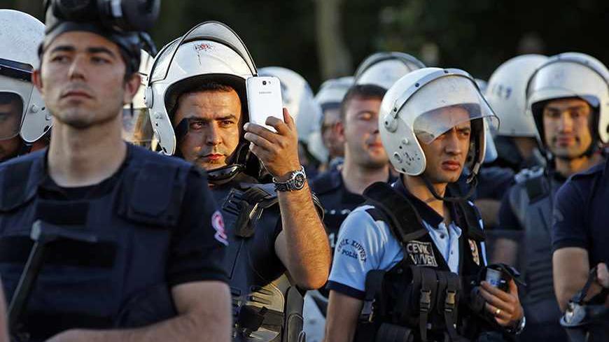 A riot policeman uses a mobile phone to film protesters at Taksim Square in Istanbul June 22, 2013. Turkish riot police fired water cannon to clear thousands of protesters from Istanbul's Taksim Square on Saturday, the first such confrontation there in nearly a week.   REUTERS/Marko Djurica (TURKEY  - Tags: POLITICS CIVIL UNREST)   - RTX10X89