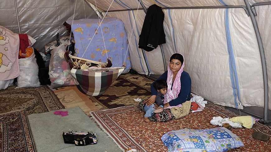 A Syrian Alawite refugee woman sits with her children in a tent at the courtyard of Pirsultan Abdal Cemevi in Istanbul October 11, 2013. As Syria's conflict takes on an increasingly sectarian dimension, a growing number of those fleeing to Turkey are shunning the refugee camps on its southern border and venturing instead to its major cities, as far from the war as possible. Picture taken October 11, 2013.    REUTERS/Murad Sezer (TURKEY - Tags: SOCIETY IMMIGRATION POLITICS CIVIL UNREST CONFLICT) - RTX14L6X