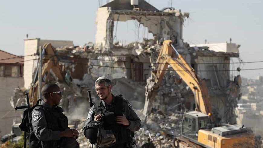 Israeli police officers stand guard as a house belonging to Palestinians is being demolished in the East Jerusalem neighbourhood of Beit Hanina October 29, 2013. A statement from the Jerusalem Municipality said there was a court order for the demolition of the house, which was built without a permit. REUTERS/Ammar Awad (JERUSALEM - Tags: POLITICS BUSINESS CONSTRUCTION) - RTX14SGL