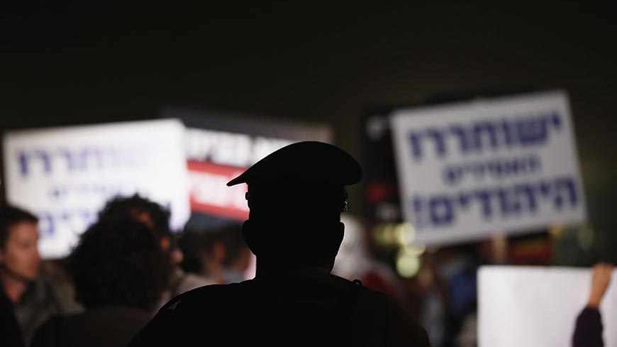 A police officer watches Israeli protesters take part in a rally against the release of Palestinian prisoners in Israeli jails outside Ofer prison near the West Bank city of Ramallah, October 29, 2013. Israel is to release 26 Palestinian prisoners in a second stage of a deal brokered by the United States in July that brought a resumption of peace talks. REUTERS/Darren Whiteside (ISRAEL - Tags: CIVIL UNREST POLITICS RELIGION) - RTX14SWY