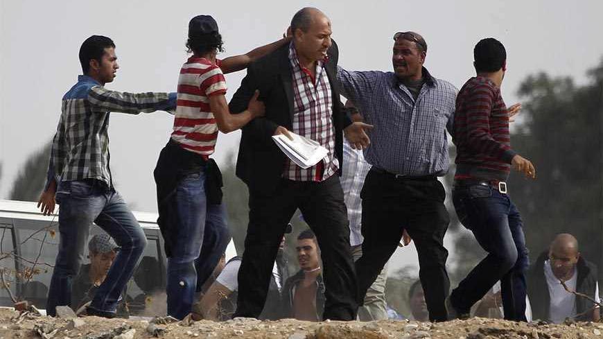 Supporters of the Muslim Brotherhood and ousted Egyptian President Mohamed Mursi push at a journalist (C), who they claim is a pro-army, as they attempt to get him to leave the area outside the police academy, where Mursi's trial took place, on the outskirts of Cairo, November 4, 2013. Mursi struck a defiant tone on the first day of his trial on Monday, chanting 'Down with military rule', and calling himself the country's only 'legitimate' president. Mursi, an Islamist who was toppled by the army in July af