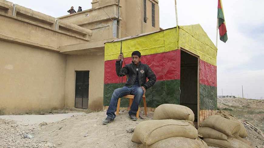 A member of the Kurdish People's Protection Units (YPG) carries his weapon as he sits at a checkpoint near the city of Ras al-Ain November 5, 2013. Redur Xelil, spokesman for the armed wing of the Syrian Kurdish Democratic Union Party (PYD), said Kurdish militias had seized the city of Ras al-Ain and all its surrounding villages. Syrian Kurdish fighters have captured more territory from Islamist rebels in northeastern Syria, a Kurdish militant group said on Monday, tightening their grip on an area where the