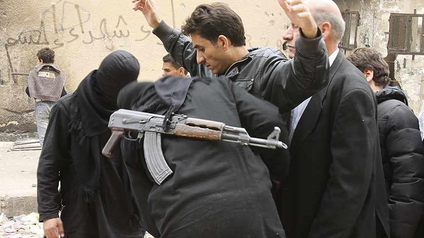 Fighters from the Islamist Syrian rebel group Jabhat al-Nusra search civilians at the Karaj al-Hajez crossing, a passageway separating Aleppo's Bustan al-Qasr, which is under the rebels' control, and Al-Masharqa neighbourhoods, an area controlled by the regime November 7, 2013. REUTERS/ Ammar Abdullah   (SYRIA - Tags: POLITICS CIVIL UNREST CONFLICT) - RTX153YY