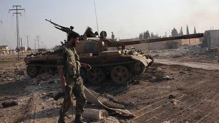 A soldier loyal to Syria's President Bashar al-Assad holds his weapon as he stands near a military vehicle in Tel Hasel, Aleppo province after capturing it from rebels November 15, 2013. State television aired a report on Friday it said was filmed in the centre of the town of Tel Hasel, 10 km (6 miles) south-east of Aleppo. The town is the third on the road to Aleppo to be taken by Assad's forces this month after the capture of Safira, close to a former chemical weapons site, and Tel Arn. REUTERS/George Our