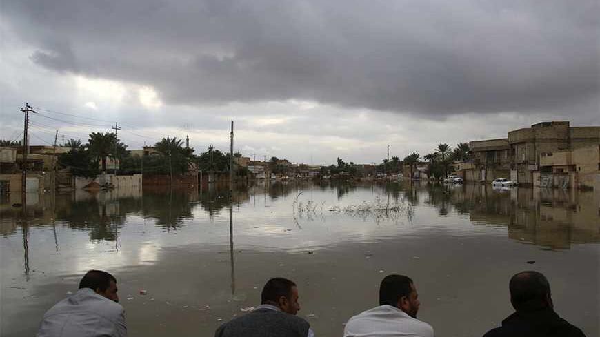 People sit on high ground watching their submerged houses after heavy rain fell in Najaf, 160 km (100 miles) south of Baghdad, November 20, 2013. REUTERS/ Ahmad Mousa (IRAQ - Tags: ENVIRONMENT DISASTER) - RTX15LZF