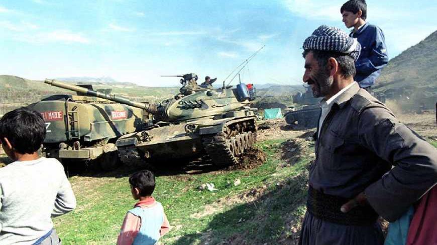 An Iraqi Kurdish pashmarga (fighter) and a group of children watch Turkish tank movement near a small village in the mountains in Northern Iraq March 22. Thirty-five thousand Turkish soldiers backed by tanks and air power entered into northern Iraq to launch an offensive against PKK Kurdish guerrillas on March 20 - RTXG5C1