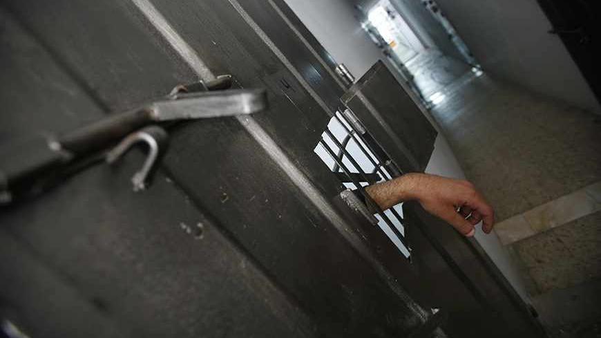 The hand of an alleged Palestinian collaborator hangs out of his cell as he speaks with a security guard inside a Hamas-run prison in Gaza City April 23, 2013. The Islamist Hamas government, which is pledged to Israel's destruction by force of arms, is lauding a recent campaign to root out informants in its midst, which it hopes will deprive Israel of a subtle but effective tool. Picture taken April 23, 2013. To match Feature PALESTINIANS-HAMAS/SPIES   REUTERS/Suhaib Salem (GAZA - Tags: POLITICS) - RTXZEXX