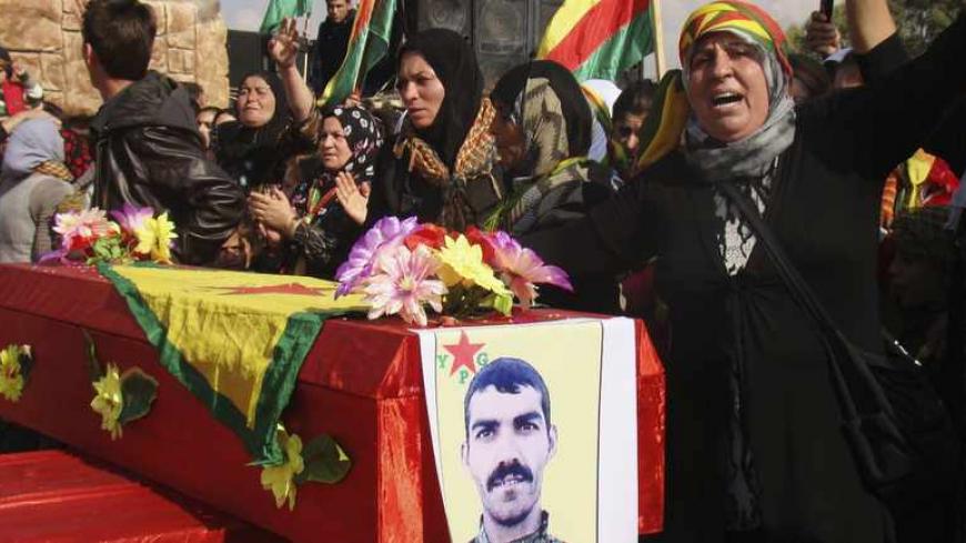 A woman stands beside the coffin of a Kurdish People's Protection Units (YPG) soldier who died fighting the al-Qaeda linked Islamic State of Iraq and the Levant, and Islamist Syrian rebel group Jabhat al-Nusra in Qamishli November 14, 2013. Picture taken November 14, 2013. REUTERS/Massoud Mohammed (SYRIA - Tags: POLITICS CIVIL UNREST CONFLICT) - RTX15H58