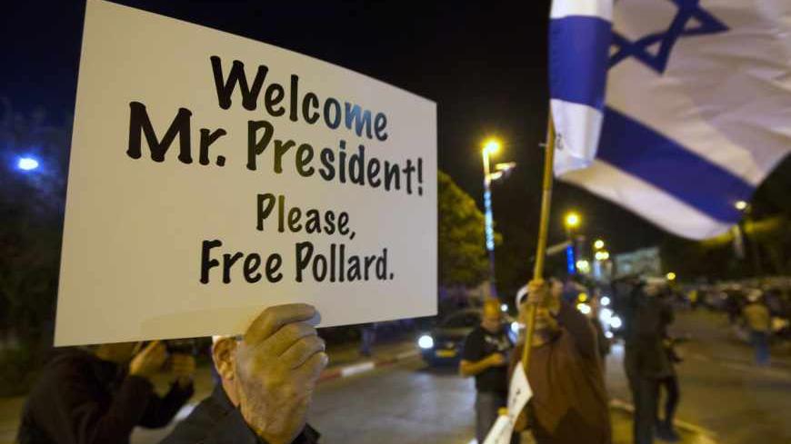 A demonstrator waves an Israeli flag as another holds a placard during a protest calling for the release of Jonathan Pollard from a U.S. prison, outside Israeli President Shimon Peres' residence in Jerusalem March 19, 2013. Some 1000 supporters protested a day ahead of Obama's visit to Israel and the occupied West Bank. Pollard, a former U.S. Navy intelligence analyst, has been serving a life sentence in the United States since he was caught spying for Israel in the 1980s. REUTERS/Ronen Zvulun (JERUSALEM - 