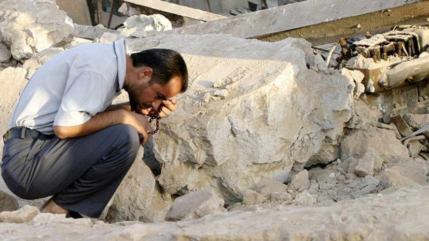 A man holds rosary beads as he inspects the ruins of a popular coffee shop after Sunday night's suicide bomb attack in the town of Tuz Khurmatu, 170 km (106 miles) north of Baghdad, July 17, 2006. Police said the attack killed 21 people. REUTERS/Slahaldeen Rasheed           (IRAQ) - RTR1FKIH