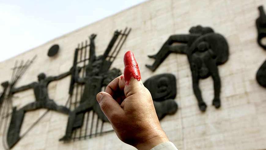 A protester holds up his red-inked finger during a demonstration at Tahrir Square in central Baghdad March 7, 2011. The protesters say they inked their fingers to show their disapproval with the government they elected in March 7, 2010, which they claim have not fulfilled its promises. REUTERS/Saad Shalash (IRAQ - Tags: CIVIL UNREST POLITICS) - RTR2JKMV