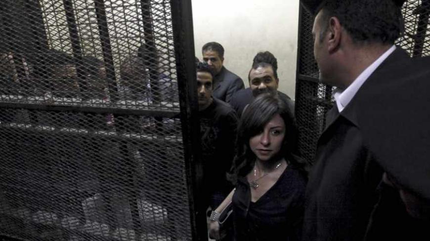 Activists, accused of working for unlicensed non-governmental organizations (NGOs) and receiving illegal foreign funds, stand in a cage during the opening of their trial in Cairo March 8, 2012. An Egyptian judge said on Thursday he was delaying until April 10 the trial of civil society activists including 16 Americans accused of receiving illegal foreign funds and pursuing their pro-democracy activities without a licence. REUTERS/Mohamed Abd El Ghany (EGYPT - Tags: CIVIL UNREST POLITICS CRIME LAW) - RTR2Z1