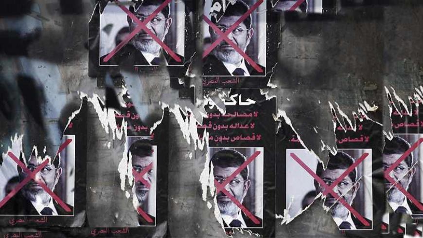 Torn posters of ousted Egyptian President Mohamed Mursi are seen on a wall at Tahrir Square in Cairo September 26, 2013. On Thursday, the groundwork for the construction of a garden was begun at the square. The poster reads, "To be on trial... No reconciliation without justice, no justice without retribution, no punishment without trial". REUTERS/Amr Abdallah Dalsh (EGYPT - Tags: POLITICS CIVIL UNREST) - RTX140EG