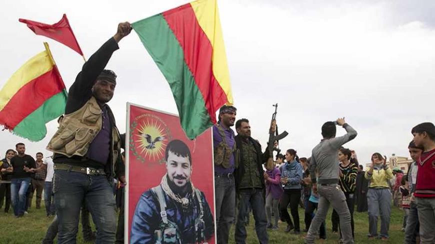 Residents and Kurdish fighters celebrate what they said was the liberation of their village from Islamist rebels near the city of Ras al-Ain November 5, 2013. The picture depicts a member of the Kurdish Youth Movement who died during the fighting. Redur Xelil, spokesman for the armed wing of the Syrian Kurdish Democratic Union Party (PYD), said Kurdish militias had seized the city of Ras al-Ain and all its surrounding villages. Syrian Kurdish fighters have captured more territory from Islamist rebels in nor