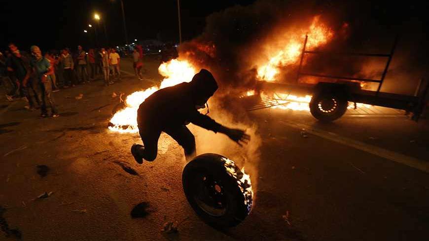 A protester rolls a burning tyre towards Israeli police during a demonstration showing solidarity with Bedouin Arabs who are against a government displacement plan for Bedouins in the Southern Negev desert in the village of Hura in southern Israel November 30, 2013. REUTERS/Baz Ratner (ISRAEL - Tags: CIVIL UNREST POLITICS TPX IMAGES OF THE DAY) - RTX15YV8