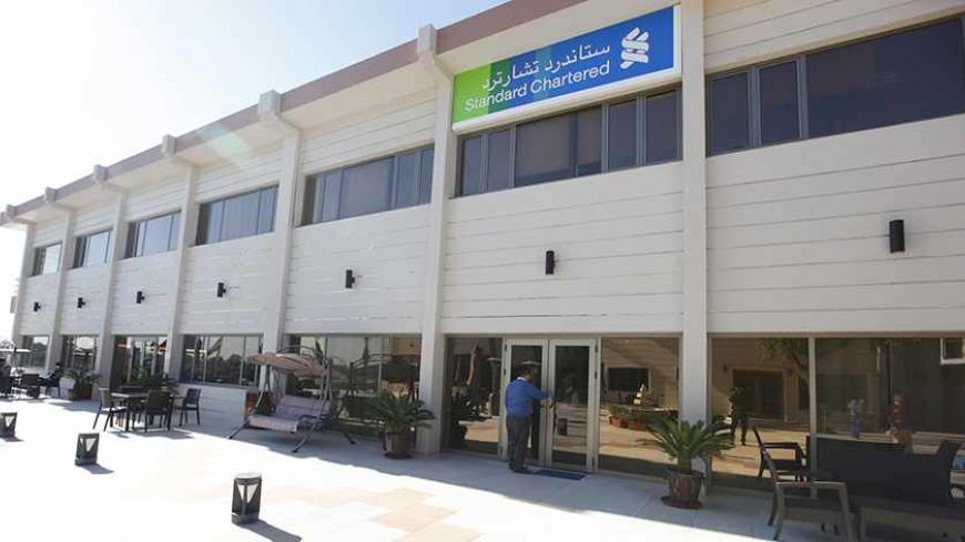 An employee of the Standard Chartered bank enters the bank in Baghdad, December 1, 2013. British lender Standard Chartered  launched banking operations in Iraq on Wednesday, saying it hoped to benefit from large infrastructure projects in a country trying to rebuild after years of conflict.  REUTERS/Ahmed Saad    (IRAQ - Tags - Tags: BUSINESS) - RTX15ZHF