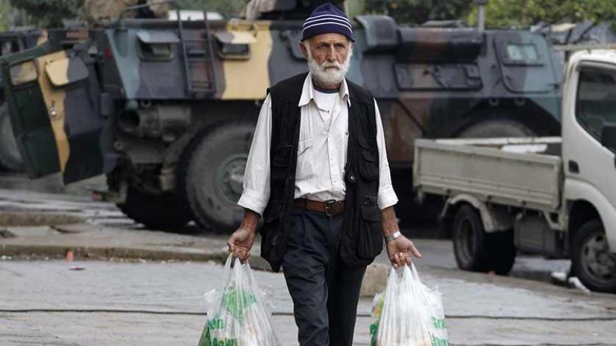A man holding groceries walks in Tripoli, northern Lebanon, December 3, 2013. The Lebanese government has told the army to take over security in the restive coastal city of Tripoli for six months, caretaker Prime Minister Najib Mikati said on Monday.Ten people were killed in weekend clashes between Tripoli's Alawite minority, which supports Syria's Alawite President Bashar al-Assad, and majority Sunni Muslims who back his foes. REUTERS/Mohamed Azakir (LEBANON - Tags: CIVIL UNREST MILITARY POLITICS) - RTX162