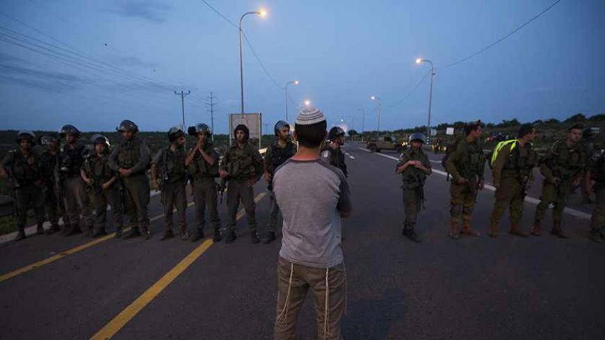 A Jewish settler stands in front of Israeli soldiers during a protest at the site of a stabbing attack by a Palestinian, at Tapuach junction, near the West Bank city of Nablus April 30, 2013. A Palestinian man stabbed and shot dead an Israeli settler in the occupied West Bank on Tuesday, the Israeli ambulance service and police said. REUTERS/Ronen Zvulun (WEST BANK - Tags: POLITICS CIVIL UNREST TPX IMAGES OF THE DAY) - RTXZ5CW