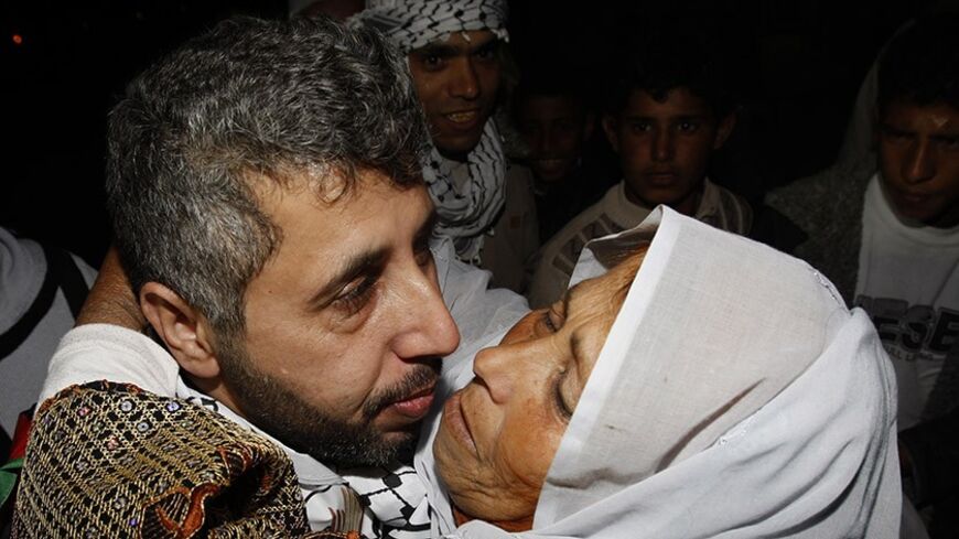 A freed Palestinian prisoner (L) is greeted by a relative upon arrival at Rafah crossing in the southern Gaza Strip December 18, 2011. Israel plans to release 550 Palestinian prisoners on Sunday in the second stage of a deal with Hamas that brought home soldier Gilad Shalit after five years of captivity in the Gaza Strip. REUTERS/Ibraheem Abu Mustafa (GAZA - Tags: POLITICS CIVIL UNREST) - RTR2VF9U