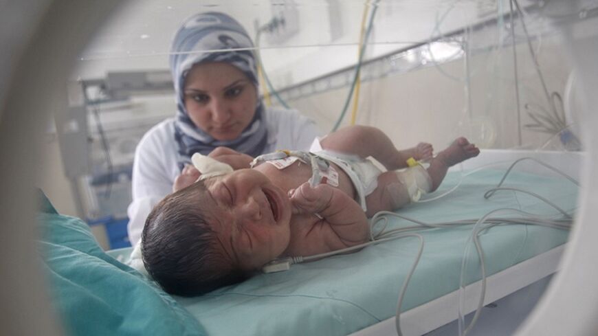 A Palestinian nurse tends to a baby inside an incubator in a hospital in Khan Younis in the southern Gaza Strip March 24, 2012. Israel allowed nine fuel tankers to cross into the Gaza Strip on Friday to ease a severe power shortage triggered by a dispute over supplies between Egypt and the enclave's Hamas Islamist rulers. The fuel crisis has crippled Gaza in recent weeks. Petrol pumps have run dry and its 1.7 million residents are suffering major electricity blackouts. REUTERS/ Ibraheem Abu Mustafa (GAZA -