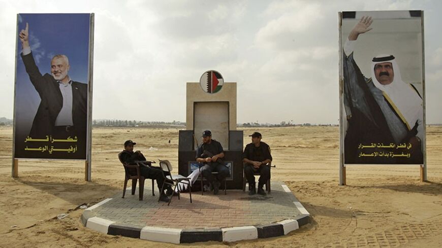 Members of Hamas security forces sit between posters depicting senior Hamas leader Ismail Haniyeh (L) and Qatar's Emir Sheik Hamad bin Khalifa al-Thani (R) in Khan Younis in the southern Gaza Strip October 22, 2012. The emir of pro-Western Qatar will become the first head of state to enter the blockaded Gaza Strip on Tuesday, in a high-profile visit breaking the isolation of the Iranian-backed Islamist movement Hamas that seized power in 2007. REUTERS/Ibraheem Abu Mustafa (GAZA - Tags: POLITICS) - RTR39F87