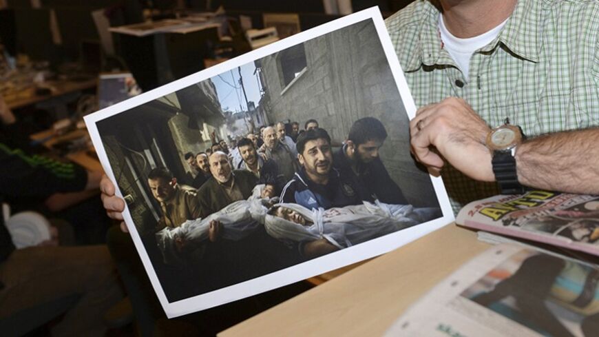 Paul Hansen of Sweden, a photographer working for the Swedish daily Dagens Nyheter, poses holding his picture that won the World Press Photo of the year for 2012, at Dagens Nyheter's office in Stockholm February 15, 2013. The photograph, which Hansen took on November 20, 2012, shows a group of men carrying the bodies of two dead children, who were killed in an Israeli missile strike on Gaza City, and won the top World Press Photo prize on Friday.        REUTERS/Fredrik Sandberg/Scanpix    (SWEDEN - Tags: ME