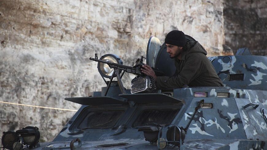 A member of al-Jabha al-Islamiya (the Islamic Front) takes position on a armoured vehicle at a checkpoint between the village of Kafaroumeh and the town of Maaret al-Naaman, to prevent members of the al Qaeda-affiliated Islamic State of Iraq and the Levant (ISIL) from advancing towards Jabal Al-Zawiya, in Idlib January 6, 2014. REUTERS/Fadi Mashan (SYRIA - Tags: POLITICS CIVIL UNREST CONFLICT) - RTX174EP