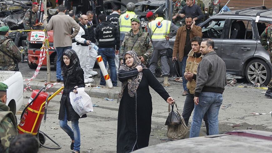 Women walk past as Lebanese army soldiers, gather at the site of Tuesday's explosion, in the Haret Hreik area in the southern suburbs of the Lebanese capital Beirut January 22, 2014. A suicide bomber killed four people on Tuesday in a residential neighbourhood of southern Beirut known for its support of Shi'ite military and political group Hezbollah, security sources said. REUTERS/Sharif Karim (LEBANON - Tags: POLITICS CIVIL UNREST) - RTX17PH5