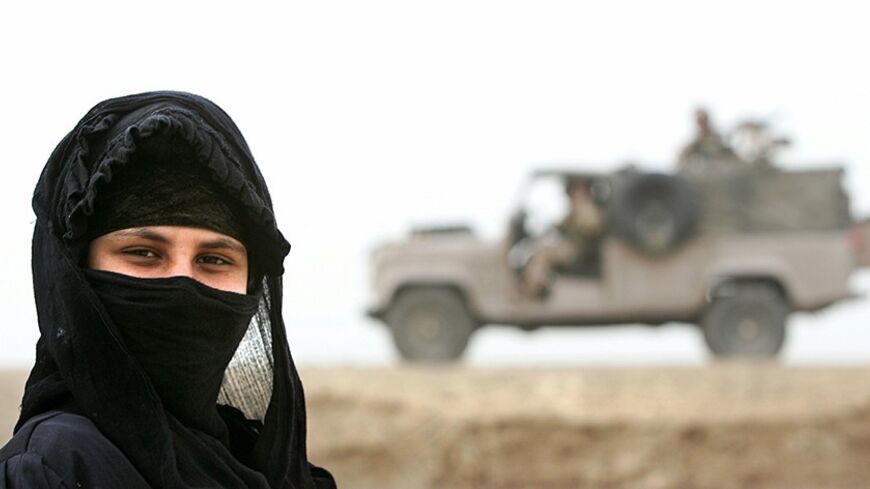 An Iraqi Marsh Arab stands as British soldiers patrol in Iraq's southern marshlands near Basra December 16, 2005, a day after [elections for the country's first full-term parliament since Saddam Hussein's overthrow. Millions of ballot papers were being counted and recounted on Friday as Iraqis celebrated a peaceful election that saw rebellious Sunni Arabs join in for the first time, pushing turnout close to 70 percent.] - RTXO2IL