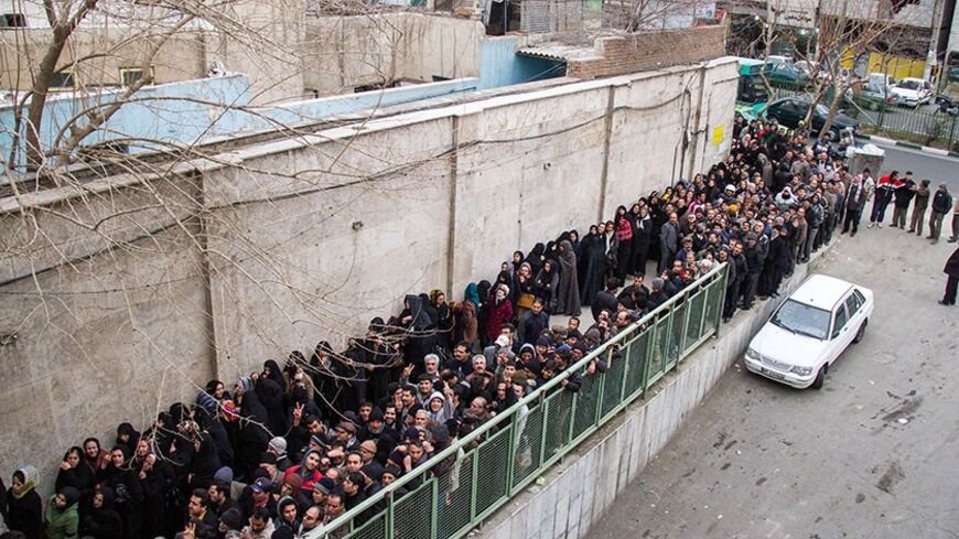 A picture taken on February 3, 2014 shows low-income Iranians lining up to receive food supplies in southern Tehran. Iranian President Hassan Rouhani faced harsh criticism from conservatives today over what they say is a poorly implemented scheme to distribute food to low-income families in the sanctions-hit Islamic republic. The programme aims to hand out packages of frozen chicken, rice, vegetable oil, cheese and eggs to poor families ahead of Iranian New Year celebrations in mid-March.  AFP PHOTO/ISNA/DA