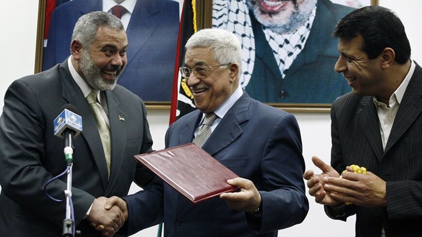 Palestinian President Mahmoud Abbas (C) gives the letter of appointment to Prime Minister Ismail Haniyeh (L) as senior Fatah leader Mohammed Dahlan watches in Gaza February 15, 2007. Abbas formally asked Haniyeh of Hamas on Thursday to form a new unity government and urged him to abide by peace accords signed with Israel. REUTERS/Suhaib Salem (GAZA) - RTR1MG8X