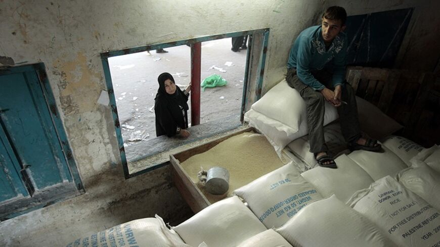 A Palestinian woman waits to receive food supplies at the United Nations Relief and Works Agency (UNRWA) headquarters in Gaza January 7, 2009. Israel and Hamas said they were temporarily holding their fire in the Gaza Strip on Wednesday to ease the flow of humanitarian aid and both sides said they were studying an Egyptian proposal for a ceasefire.        REUTERS/Mohammed Salem (GAZA) - RTR234UE