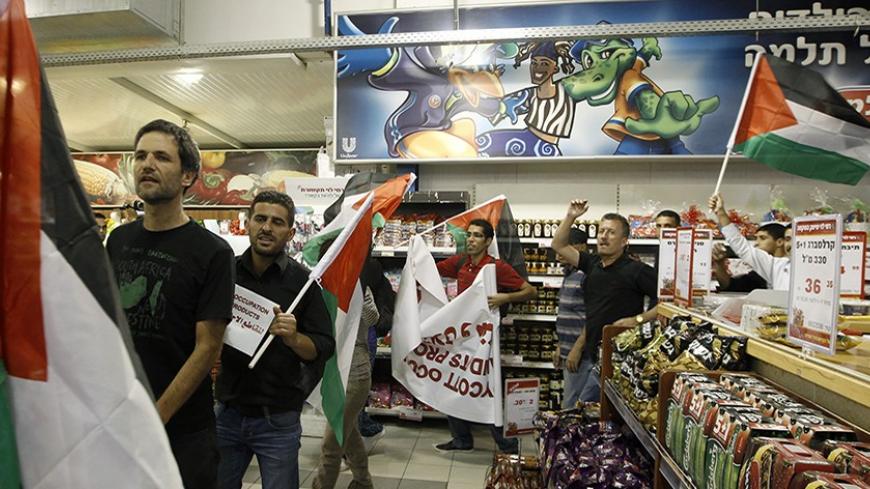 Foreign and Palestinian activists hold Palestinian flags as they march through a supermarket in the West Bank Jewish settlement of Modiin Illit October 24, 2012. Some 50 activists marched through the supermarket and tried to block a road in the settlement on Wednesday during a protest against Jewish settlements and in a call to boycott settlement products. REUTERS/Ammar Awad (WEST BANK - Tags: POLITICS CIVIL UNREST FOOD TPX IMAGES OF THE DAY) - RTR39IM8