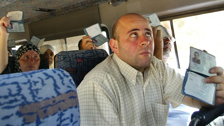 Palestinians show their ID cards to Israeli police inside a bus in Jerusalem August 12, 2004. Investigators were still examining if members of a militant cell which bombed a West Bank checkpoint Wednesday were still at large. The blast killed two Palestinians and wounded 16 people. REUTERS/Gil Cohen Magen GCM/SM - RTR8GY0