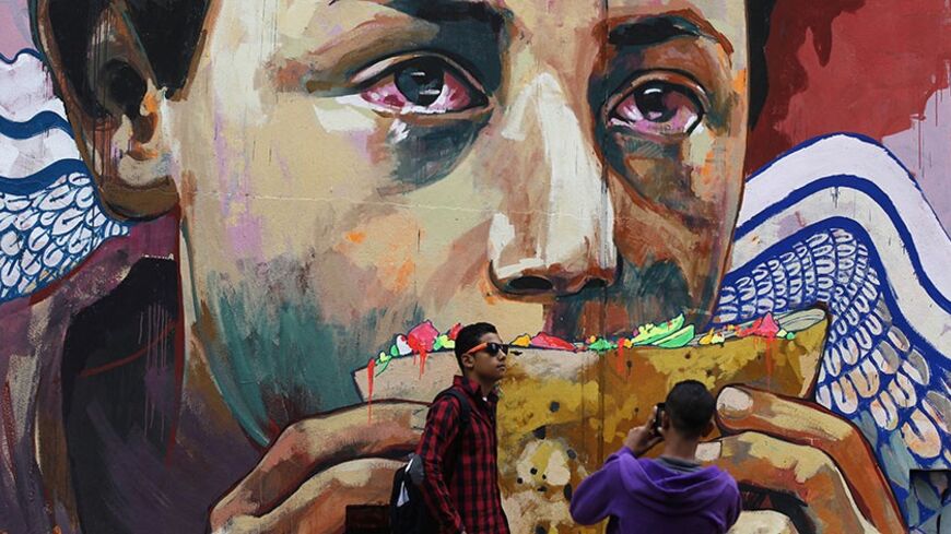 Youths take photos in front of graffiti depicting poverty and homelessness in downtown Cairo December 5, 2013. The Egyptian pound was steady at official rates on Thursday, the central bank said, and slightly stronger in the black market, two sources said - a day after the bank's governor said that parallel market for dollars would "not last long". REUTERS/Amr Abdallah Dalsh (EGYPT - Tags: POLITICS SOCIETY BUSINESS TPX IMAGES OF THE DAY) - RTX164R2