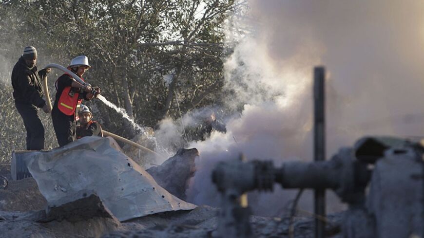 A member of Palestinian civil defense extinguishes a fire at a Hamas training camp after it was hit by an Israeli air strike in Khan Younis in the southern Gaza Strip December 24, 2013. A Gaza sniper shot dead an Israeli civilian over the border on Tuesday and Israel hit back with air strikes on two Hamas training camps which hospital officials said killed a Palestinian girl near one of the targets. REUTERS/Ibraheem Abu Mustafa (GAZA - Tags: POLITICS CIVIL UNREST) - RTX16TBF