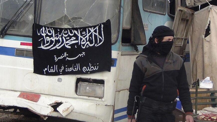 A member of Islamist Syrian rebel group Jabhat al-Nusra mans a checkpoint on the border crossing between Syria and Jordan, which they claim to have taken control of, in Daraa December 26, 2013. Flag reads, "There is no God but Allah, and Muhammad is his prophet. Al-Nusra front, al-Qaeda in the Levant". Picture taken December 26, 2013. REUTERS/Ammar Khassawneh (SYRIA - Tags: POLITICS CIVIL UNREST CONFLICT) - RTX16VW7