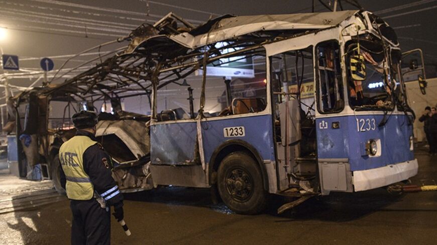 A policeman watches as a bus, destroyed in an earlier explosion, is towed away in Volgograd December 30, 2013.  A bomb ripped apart a bus in Volgograd on Monday, killing 14 people in the second deadly attack blamed on suicide bombers in the southern Russian city in 24 hours and raising fears of Islamist attacks on the Winter Olympics. REUTERS/Sergei Karpov (RUSSIA - Tags: CIVIL UNREST CRIME LAW DISASTER TRANSPORT) - RTX16XGD