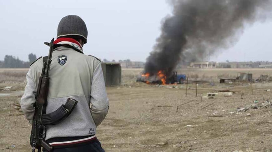 A Sunni Muslim fighter looks at a burning police vehicle during clashes in Ramadi January 2, 2014. Sunni Muslim fighters clashed on Thursday with Iraqi troops trying to regain control of two western cities, in a serious escalation of their confrontation with the Shi'ite-led government of Prime Minister Nuri al-Maliki. Tension has been running high in the Sunni-dominated province of Anbar since Iraqi police broke up a Sunni protest camp on Monday, leaving at least 13 people dead.  REUTERS/Ali al-Mashhadani (