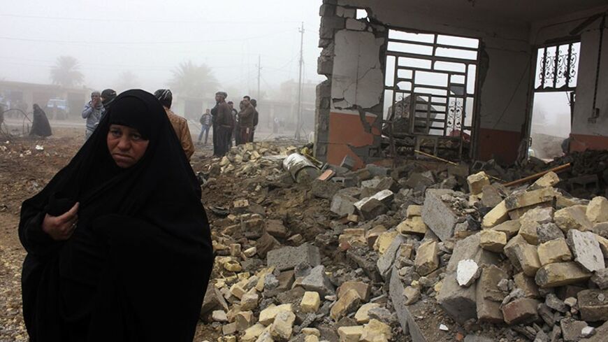 A woman walks past the site of a bomb attack in Balad Ruz, in northeastern Iraq, January 3, 2014. A suicide bomber driving a car packed with explosives killed at least 12 people who had gathered to buy and sell cars in Iraq on Thursday, local officials said. No group immediately claimed responsibility for the attack, which took place near the car markets in the town of Balad Ruz, in northeastern Iraq, injuring another 25 people.   REUTERS/Mohammed Adnan (IRAQ - Tags: CIVIL UNREST) - RTX170P9