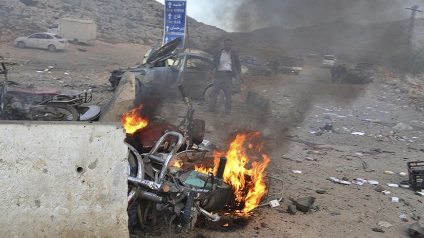 A man stands near a burning motorbike at the site of a car bomb attack at the Bab al-Hawa border crossing between Syria and Turkey, in Idlib January 20, 2014. Two car bombs hit a rebel-held border post in the northwest Syrian province of Idlib on Monday, opposition activists and fighters said, killing at least 10 people and closing the frontier. The Bab al-Hawa crossing is held by a rebel alliance called the Islamic Front, which have been fighting with the al Qaeda-linked Islamic State in Iraq and the Levan