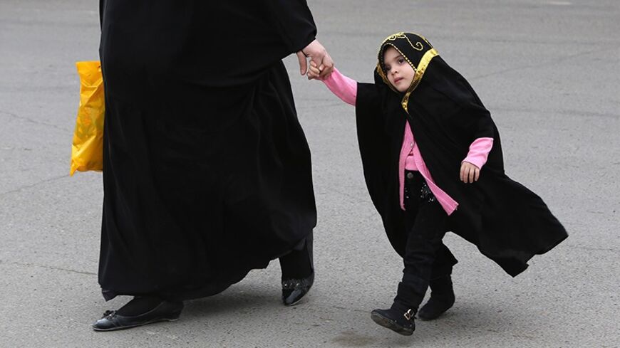 TO GO WITH AFP STORY BY AMMAR KARIM
An Iraqi woman walks with her fully veiled daughter in Baghdad on March 18, 2014. A bill before Iraq's parliament that opponents say legalises child marriage and marital rape has sparked controversy ahead of elections as secular activists face off against the draft law's backers. The bill, the Jaafari Personal Status Law, sets out rules to do with inheritance, marriage and divorce. Supporters of the draft, named after a Shiite Muslim school of jurisprudence, say it simply