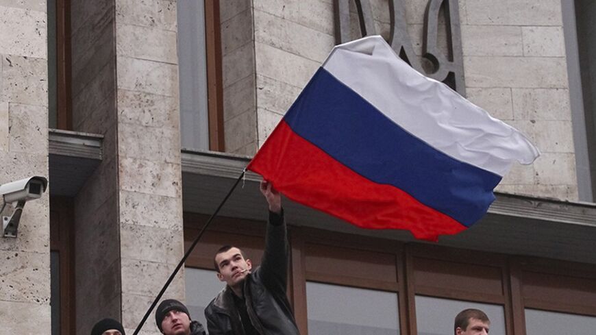 Pro-Russian demonstrators erect a Russian flag outside the regional government building in Donetsk March 5, 2014. Pro-Moscow youths recaptured the administrative headquarters of the eastern city of Donetsk and flew the Russian flag from its roof on Wednesday, hours after Kiev's authorities managed to fly their own flag there for the first time since Saturday. REUTERS/Stringer (UKRAINE - Tags: POLITICS CIVIL UNREST) - RTR3G2UQ