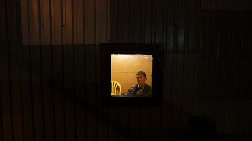 A member of the local Crimean Tatar community looks out of a makeshift shelter to keep watch against pro-Russian supporters near their houses on the outskirts of Simferopol, March 9, 2014. An armed pro-Russian force wearing military uniforms bearing no designated markings sealed off another military airport in Ukraine's Crimea on Sunday, a defence ministry spokesman on the peninsula said.  REUTERS/Vasily Fedosenko (UKRAINE - Tags: POLITICS CIVIL UNREST) - RTR3GCMU