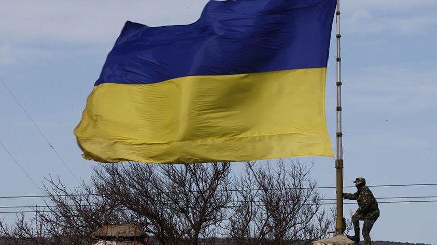 A Ukrainian soldier climbs a flag pole at the base A2904 shortly before the Ukrainian command lost control over it to armed men in the Crimean town of Bakhchisaray March 10, 2014. Russian forces consolidated their hold on Ukraine's Crimea peninsula on Monday, taking over a military hospital and a missile base as officials geared up for a referendum on the region's future.  REUTERS/Thomas Peter (UKRAINE  - Tags: POLITICS MILITARY) - RTR3GFVD