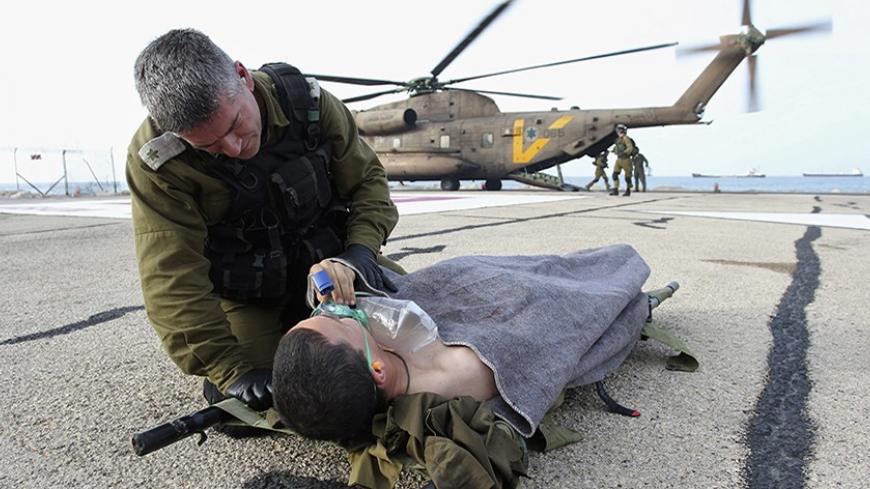 An Israeli army officer speaks to a soldier who was wounded during an explosion as he is evacuated to hospital, in the northern city of Haifa March 18, 2014. A roadside bomb wounded four Israeli soldiers patrolling the occupied Golan Heights on Tuesday, and Israel retaliated with artillery fire on Syrian army positions, the army said. It was not clear who had planted the bomb in an area where the Syrian military, Lebanese Hezbollah guerrillas and Syrian rebels fighting President Bashar al-Assad all have a p