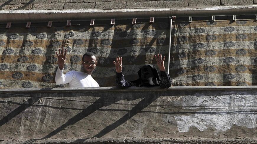 People raise their hands with the sign of Muslim Brotherhood supporters from their balcony during a protest by supporters of the Muslim Brotherhood in Matarya area, east of Cairo, March 21, 2014. REUTERS/Al Youm Al Saabi Newspaper (EGYPT - Tags: POLITICS CIVIL UNREST) EGYPT OUT. NO COMMERCIAL OR EDITORIAL SALES IN EGYPT - RTR3I2B6